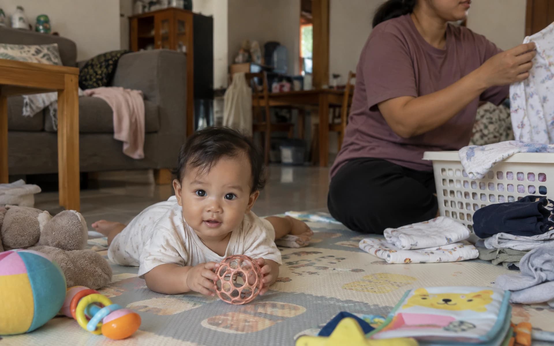 Bayi bermain di lantai bersama orang tuanya di rumah