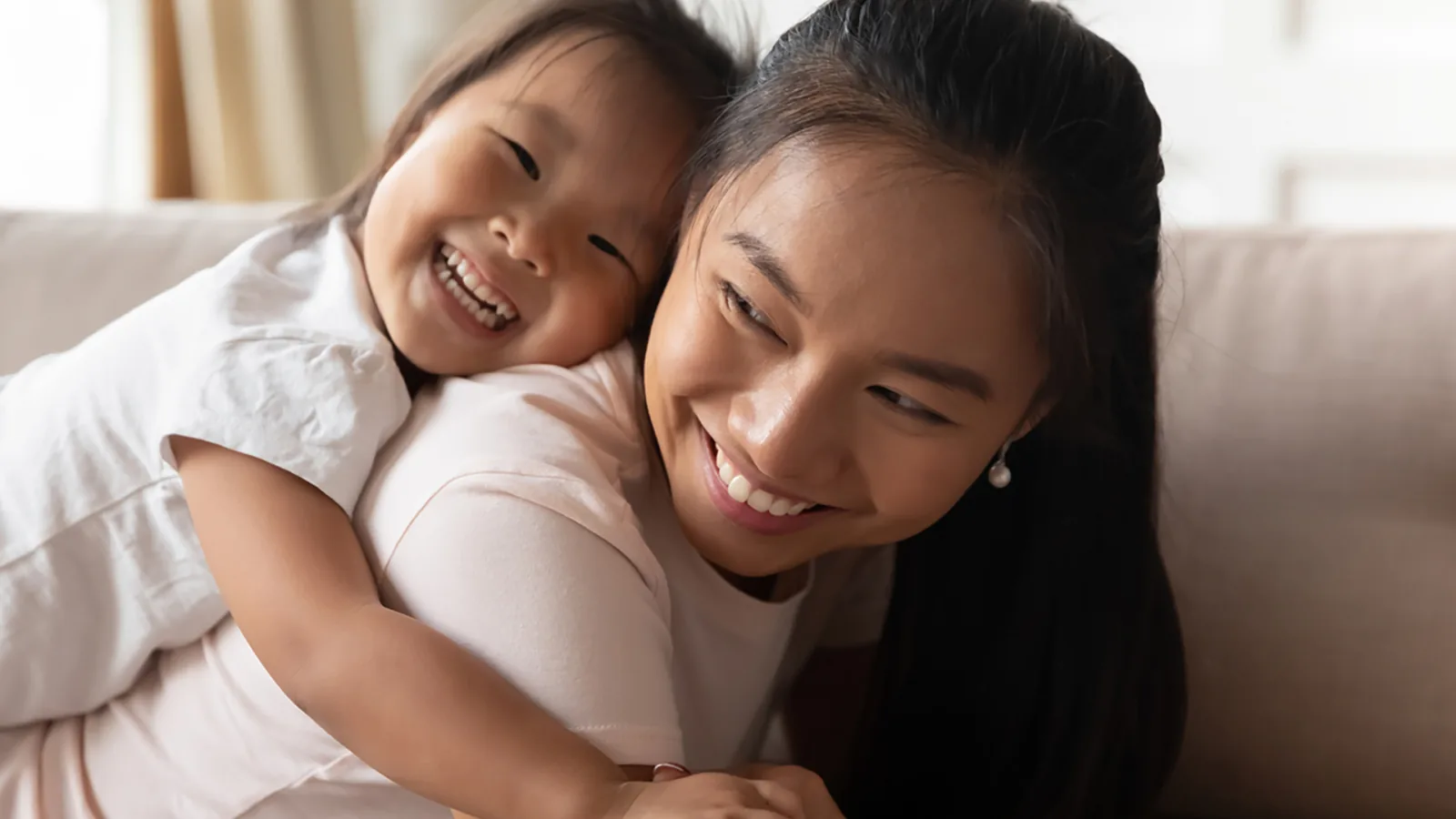 Anak memeluk ibunya di sofa