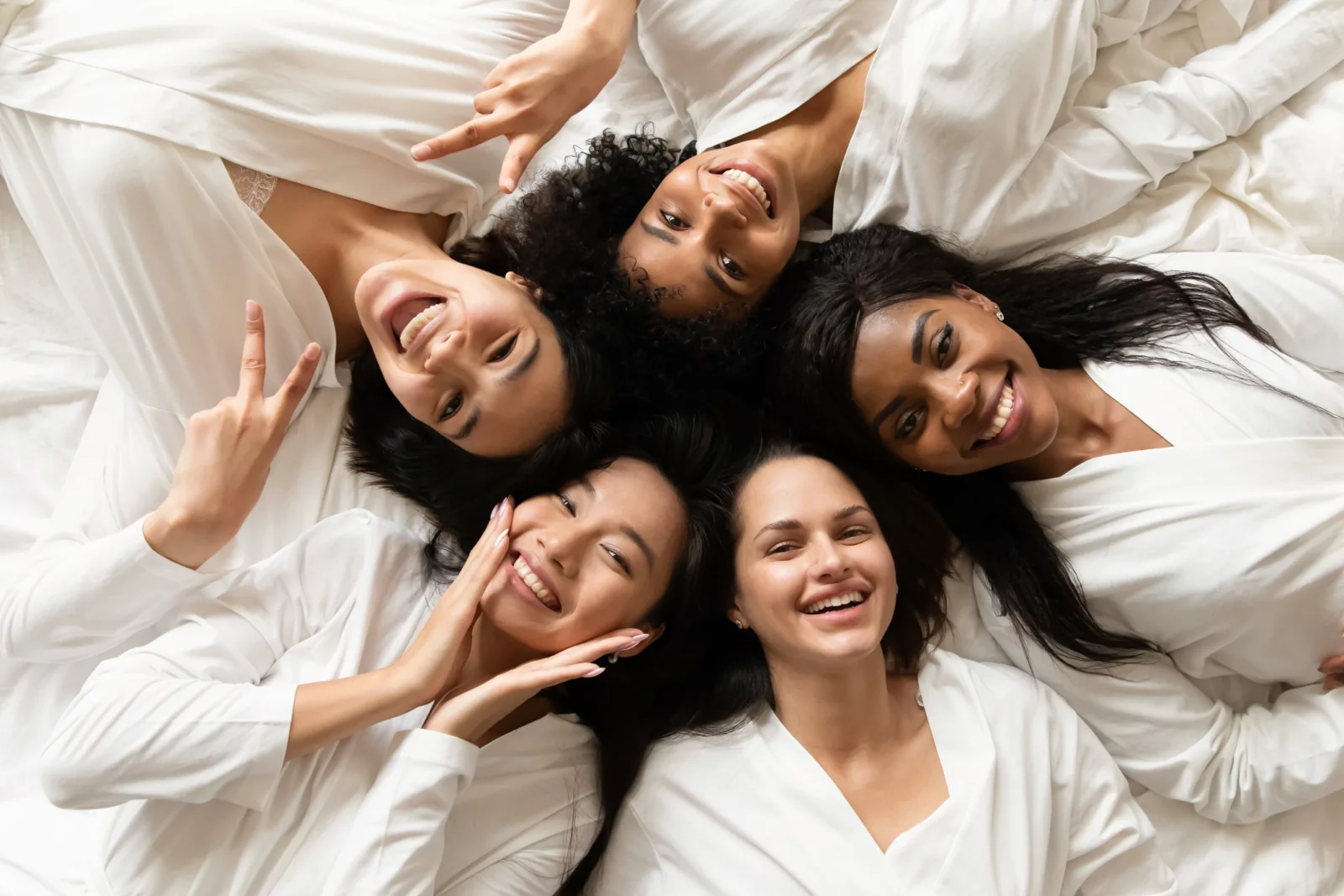 Empat perempuan berbaring bersama sambil tertawa