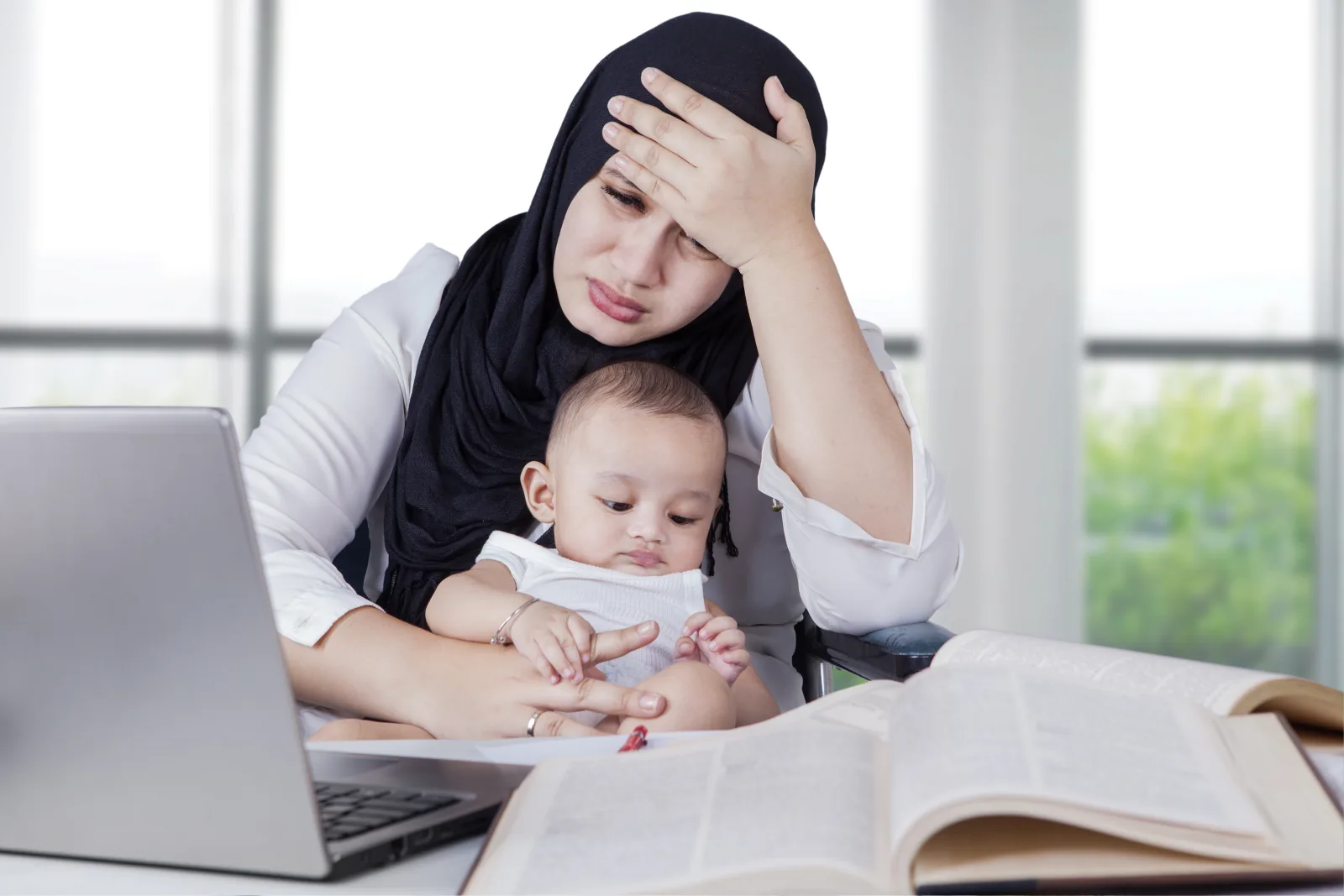 Ibu berhijab tampak lelah menggendong bayinya