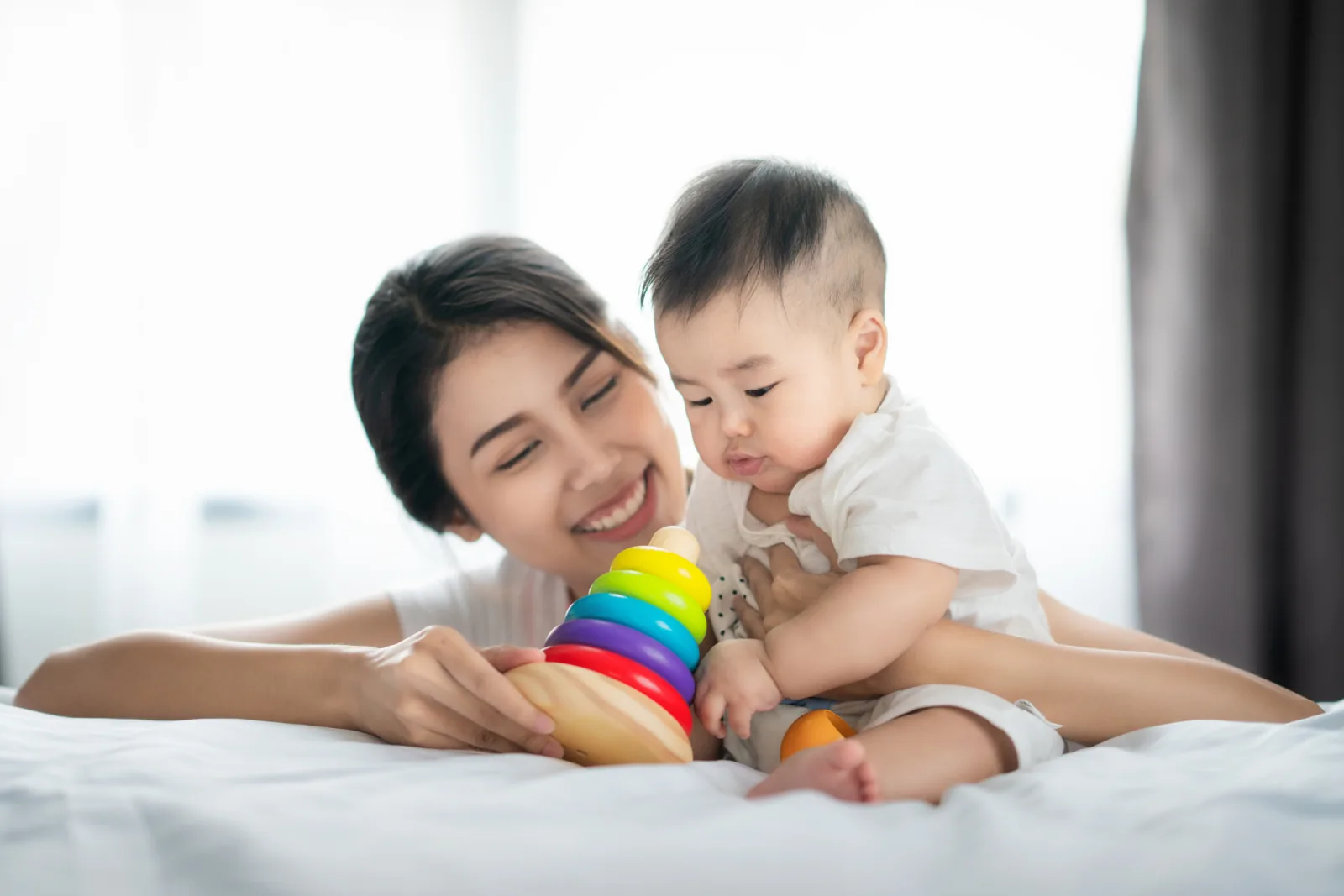 Ibu bermain bersama bayinya di atas kasur