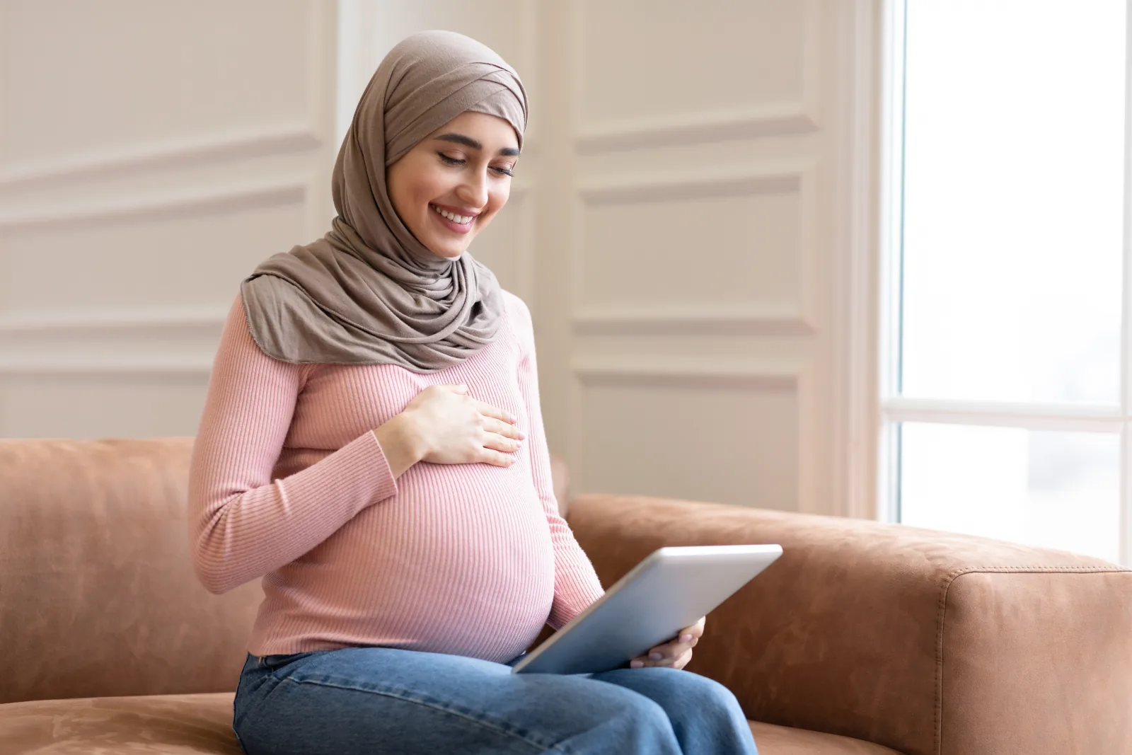 Ibu hamil berhijab melihat ponsel