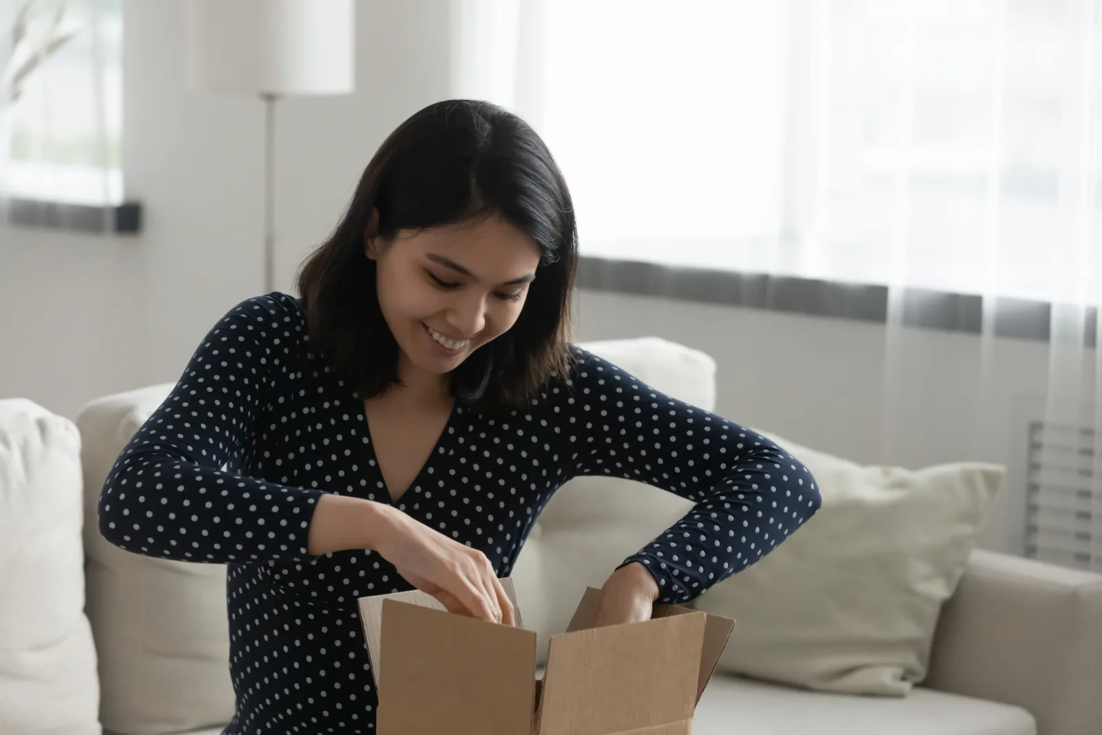 Perempuan membuka paket di ruang tamu