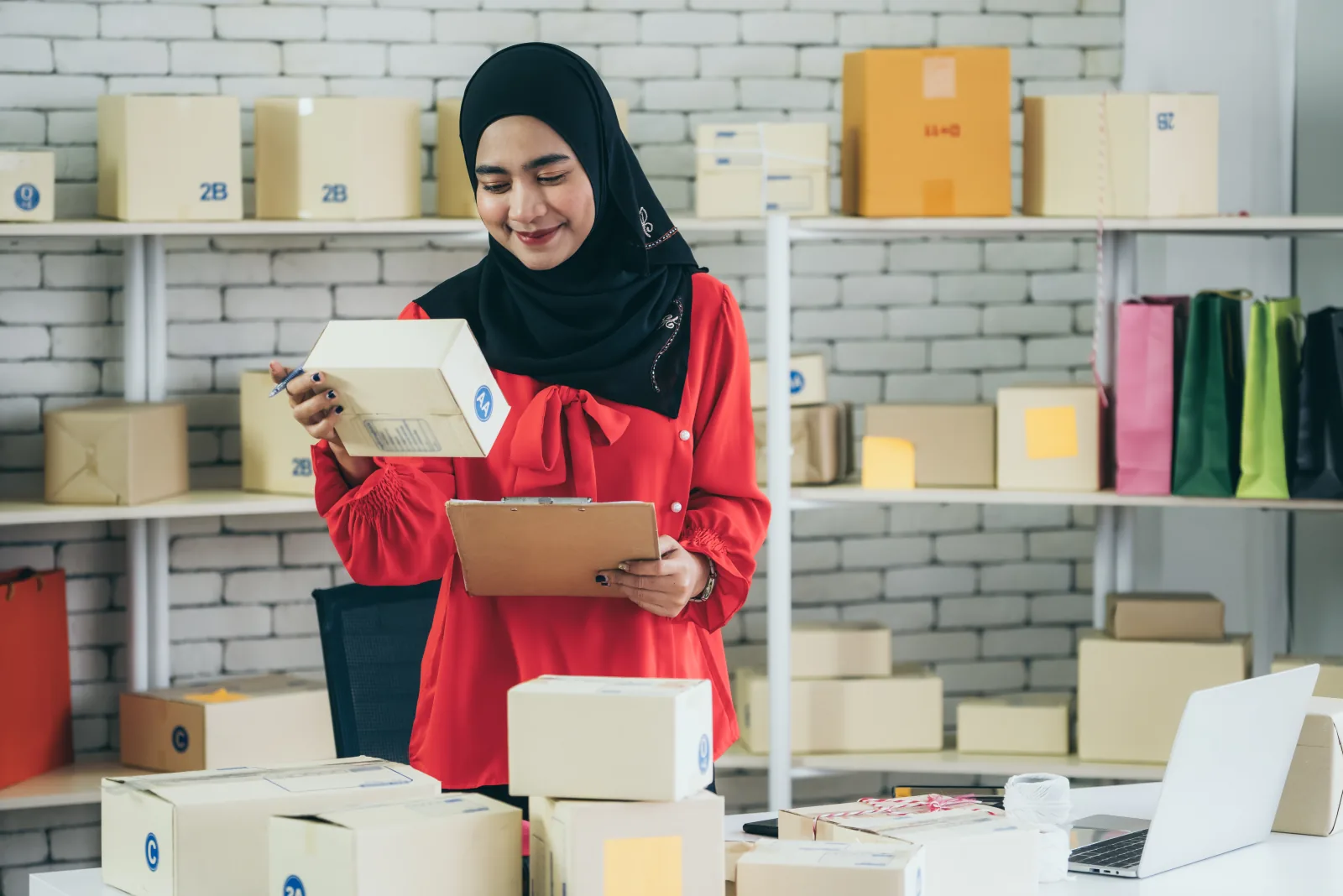 Perempuan berhijab mendata paket di gudang